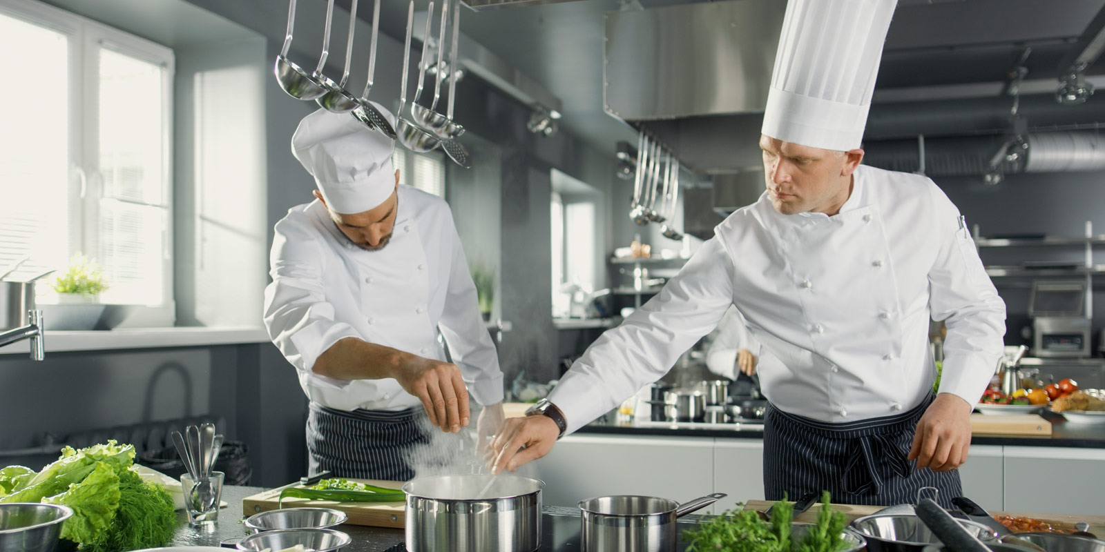 due chef preparano il pranzo in una cucina con ventilazione Menerga